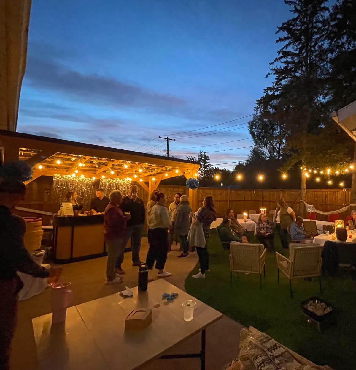 Pop-up bar under string lights at a backyard party at dusk